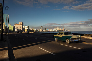Old car on Malecon street of Havana with beautiful buildings in background. Cuba