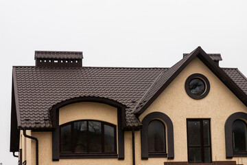 The roof of the house is made of red metal tiles, a beautiful large chimney