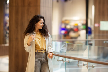 Young cheerfful woman drinking take away coffee in paper cup.