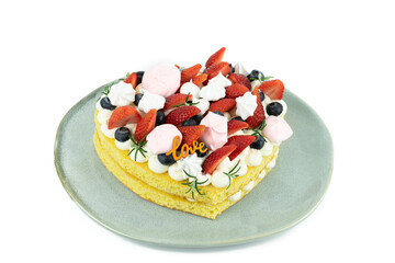 Heart-shaped cake decorated with red fruits and meringue. White background. Valentine's Day. Copy space.