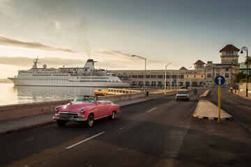 Old car on Malecon street of Havana with sunrise in background. Cuba