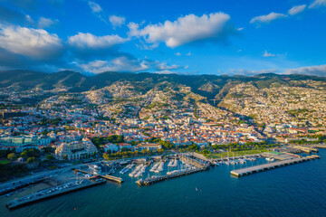 Aerial drone view of Funchal city center and port panorama in Madeira island in the evening. It's Portugal's Autonomous Region and is located in Atlantic ocean - obrazy, fototapety, plakaty