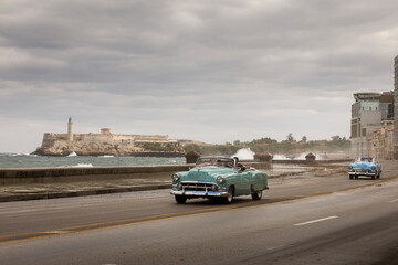Old car on Malecon street of Havana with storm clouds in background. Cuba