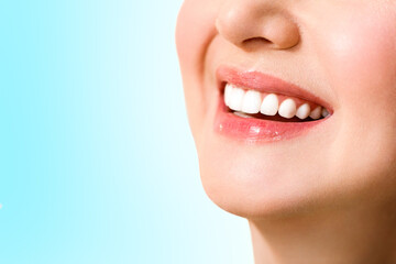 Beautiful female smile after teeth whitening procedure. Dental care. Dentistry concept. On a blue background.