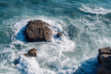 Aerial drone view of the ocean and waves crashing on rocks.