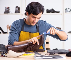 The young man repairing shoes in workshop