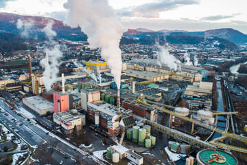 Aerial view of a huge factory facility during sunset with lots of smoke coming out of the chimneys