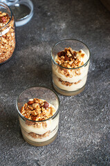 Granola with yogurt dessert in a glass. Gray background. Healthy eating or breakfast concept.