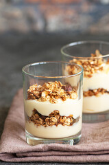 Granola with yogurt dessert in a glass. Gray background. Healthy eating or breakfast concept.
