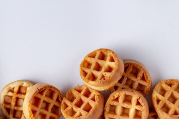 round small waffles are scattered on a white background, space for text