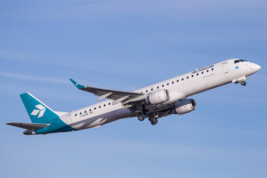 Air Dolomiti Embraer jet departing Graz aerodrome on a clear winterday with blue sky