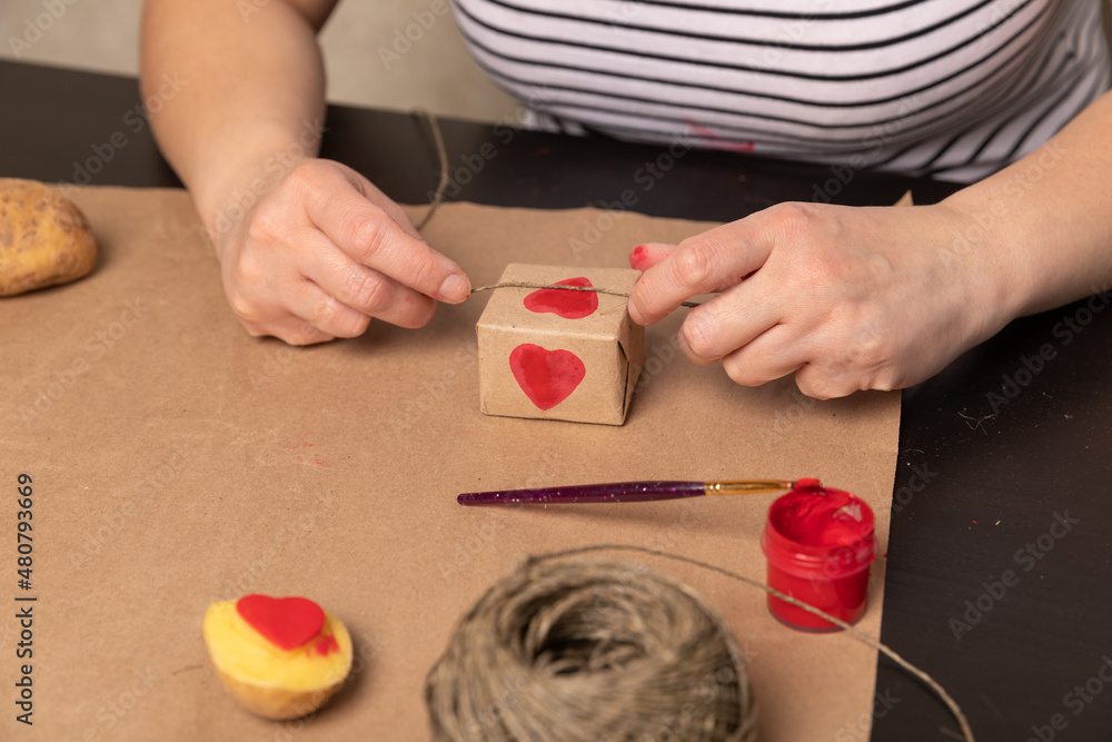 Wall mural heart shaped potato stamp on craft paper. The process of decorating a gift for Valentine's Day. Getting ready for the celebration on February 14th.