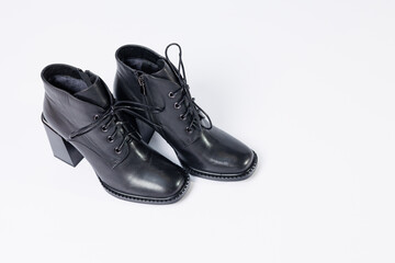 Women's boots with black genuine leather on heels isolated on a white background. photo from the side, diagonally and foreshortened from behind. Women's shoe collection 2022