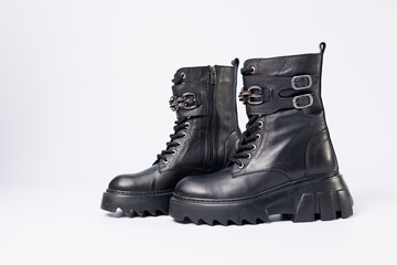 Women's shoes on a white background. Close-up of women's black leather boots with buckles on a white background. Shoes for the city. Concept for 2022 fashion, design and footwear.