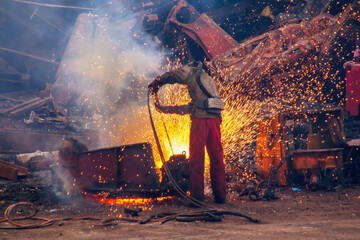 Man cutting scrap steel with a gas cutting torch.
