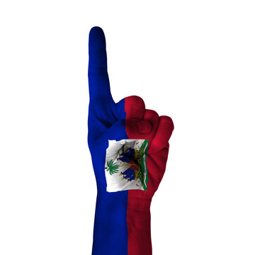 Hand pointing thumb up direction, haiti painted with flag as symbol of up direction, first and number one symbol - isolated on white background
