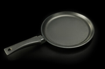 New clean frying pan, on black background 