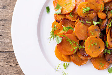 roasted carrots on a white plate on wooden table