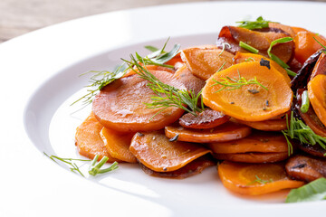 roasted carrots on a white plate on wooden table