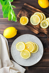 Round pieces of ripe lemons on a plate and on a wooden cutting board on the table. Organic nutrition, source of vitamins. Top and vertical view