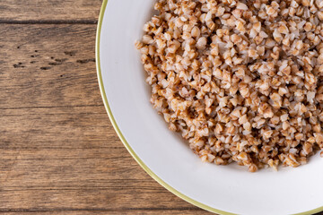 buckwheat in a white plate on a wooden background