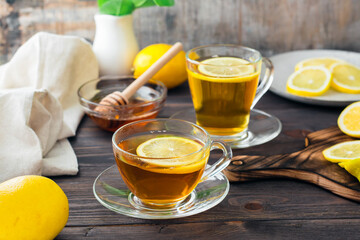 Two cups of tea with lemon and a bowl of honey on a wooden table. Vitamin warming drink