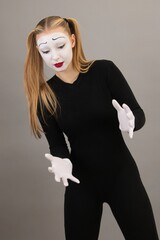 The girl-artist in the role of pantomime holds an invisible ball.