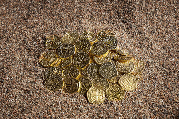 Old gold coins in the sand. Treasure discovering concept. Selective focus.