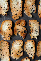 Pattern of home-cooked snacks of salted bread chips, on a black background