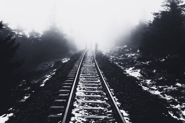 Wanderer laufen auf den Gleisen im Winter bei Nebel