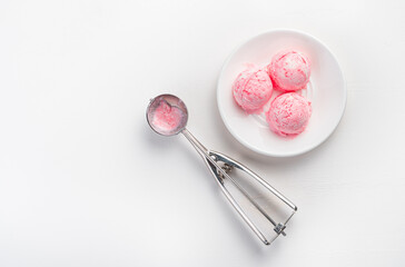 Three balls of berry ice cream and a scoop on a white background with space to copy.