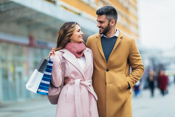 Portrait of happy couple with shopping bags after shopping in city.