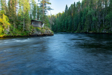 Kitka river landscape with a wooden cottage on the riverbank by Pieni Karhunkierros hiking trail in Oulanka national park, Northern Finland, Europe. - obrazy, fototapety, plakaty