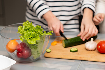 Fresh vegetables in a transparent plate on the table. Healthy eating. Nearby you can see the hands of a man who cuts a salad. The concept of healthy food. Health care.