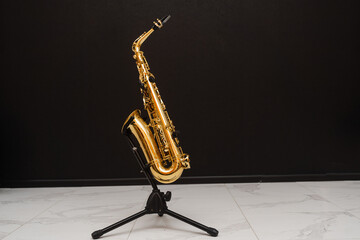 Saxophone musician instrument on stand on black background. Sax musical instrument for play jazz.