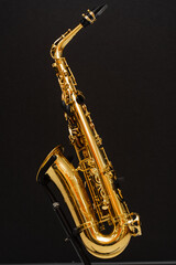 Naklejka premium Saxophone musician instrument on stand on black background. Sax musical instrument for play jazz.