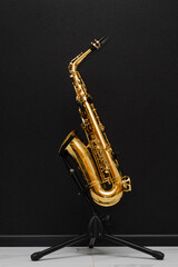 Sax musical instrument for play jazz. Saxophone musician instrument on stand on black background.