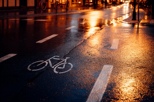 Fahrradweg im Dunkel mit nasser Fahrbahn. Reflexion der Straßenlichter