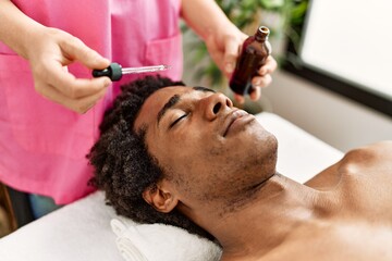 Fototapeta na wymiar Young african american man having skin face treatment at beauty center