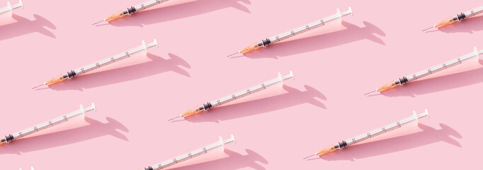 Banner Creative medicinal pattern from syringes of pink background. Colorful concept of New Corona virus 2019-nCoV or COVID-19 vaccine. Flat lay, top view.