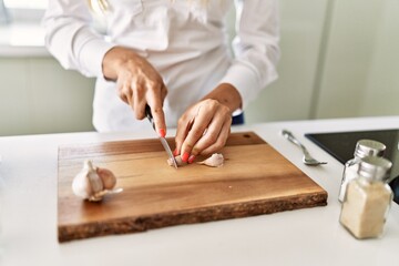 Fototapeta na wymiar Young blonde woman cutting garlic at kitchen