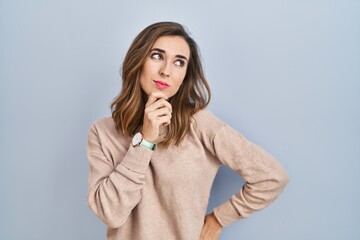 Young woman standing over isolated background with hand on chin thinking about question, pensive expression. smiling with thoughtful face. doubt concept.