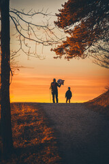 Fototapeta na wymiar Father and son stand in front of the beautiful sunset. Silhouette.
