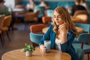 a business lady in a turquoise or blue business suit sits at a table in a cafe. cafe interior in turquoise and brown colors. The woman has light hair
