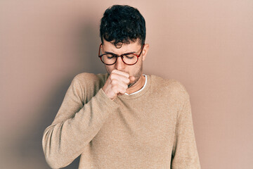 Young hispanic man wearing casual clothes and glasses feeling unwell and coughing as symptom for...