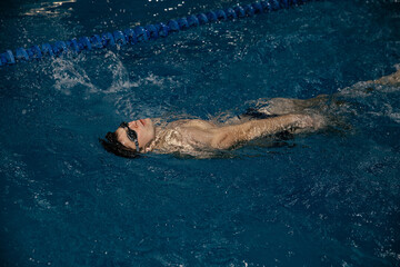 Obraz premium Man in the pool. Floating on his back. A swimmer trains in the pool on the track