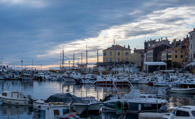 Fototapeta na wymiar Anchored sailing boats in the Rovinj city port, during winter sunset