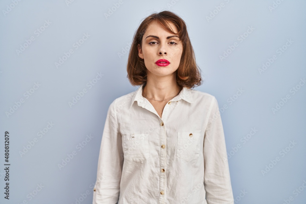 Sticker young beautiful woman standing casual over blue background relaxed with serious expression on face. 