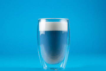 Blue anchan matcha latte on blue background. Matcha cocktail in double glass cup.