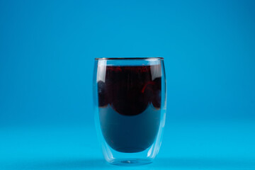 Blueberry tea in double glass cup on blue background..